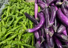 Green long hot peppers from China sit in contrast to the dark purple Chinese eggplant from Mexico.