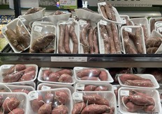 Purple potatoes are packaged and on the store shelf just above sweet potatoes.