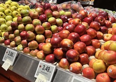 A long row of many loose apple varieties for shoppers to choose from.