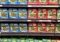 A wall of branded leafy green and salad blends sit right next to...