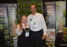 Charity Carson and Jorge Michael with Rocket Farms, standing in front of a large display of herbs.