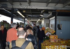 Trucks are being loaded on the left. To the right, buyers can see the produce and pay at the cashier booths.