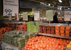 A large selection of tomatoes on display and basil placed with it.