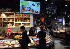 Entrance to the Yonghui Superstores shop. In the middle television screens that show shots of New Zealand kiwifruit orchards and kiwifruit sorting and packaging processes.