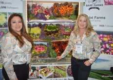 Rocio Munoz and Ande Manos with Babe Farms stand in front of a colorful display of specialty vegetable items.