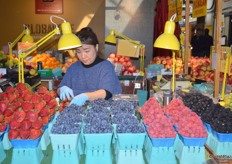 One of the vendors make trays with berries ready for display.