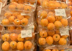 Loquats. The more exotic fruit and vegetable varieties are all sold on trays and wrapped in plastic.