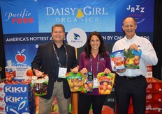 Smiles in the booth of CMI Orchards. Bob Mast holds pouch bags with Northwest cherries and pears. Danelle Huber shows Kanzi and Ambrosia apples while George Harter holds Kiku and organic Fuji apples.