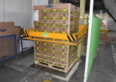 A pallet of kiwis is mechanically being made ready for transport.